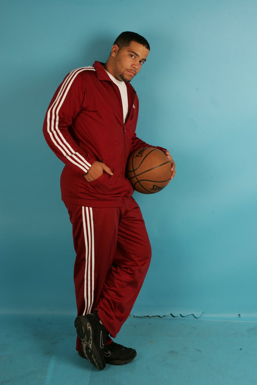 man wearing a red tracksuit holding a basketball