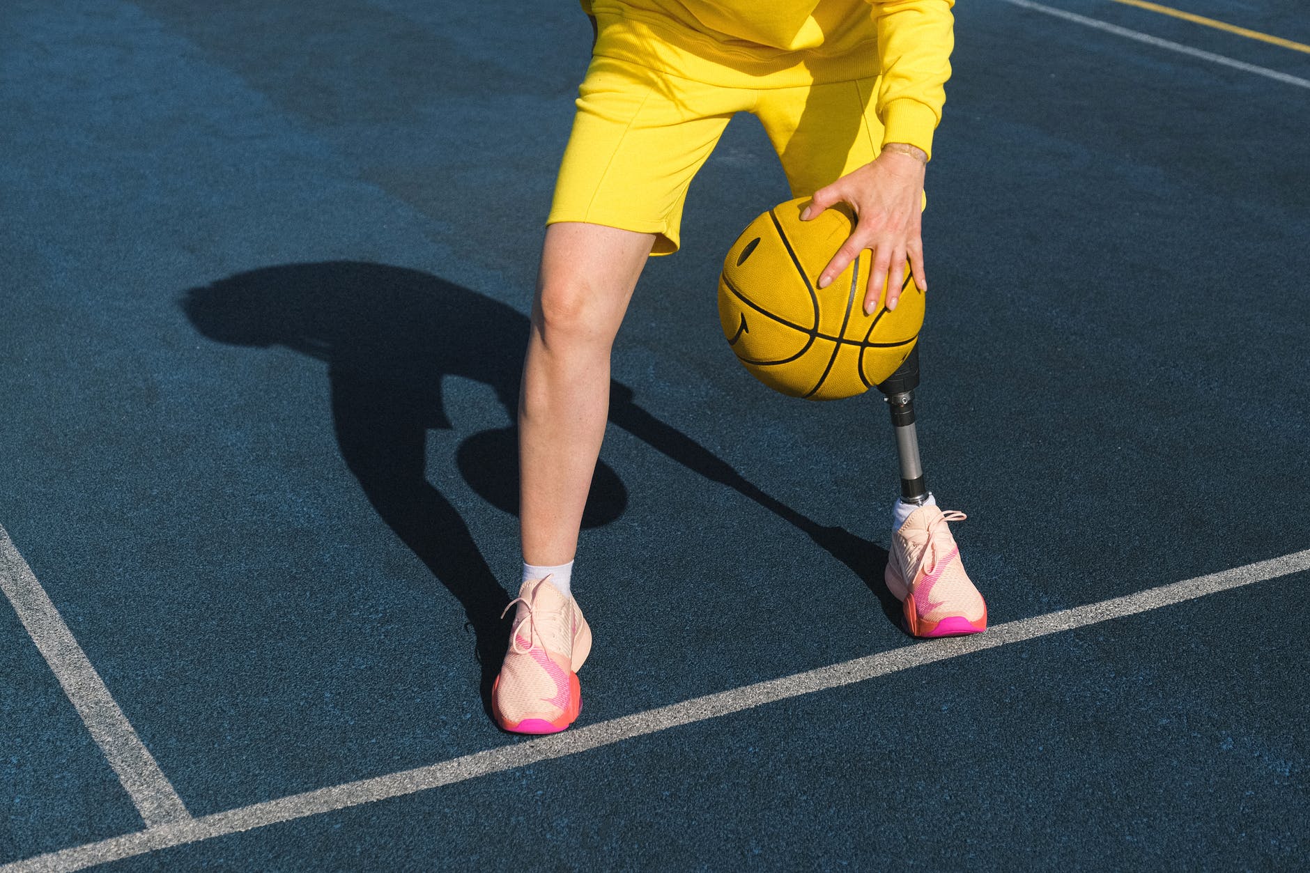 woman in yellow shorts and pink flats holding basketball