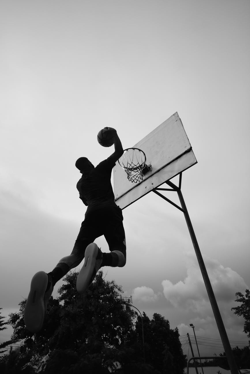 tall sportsman throwing ball in basketball hoop