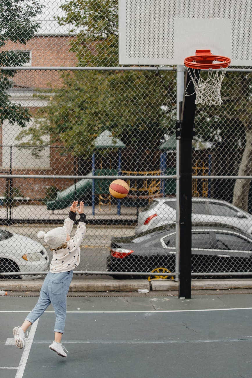 anonymous girl playing basketball on playground