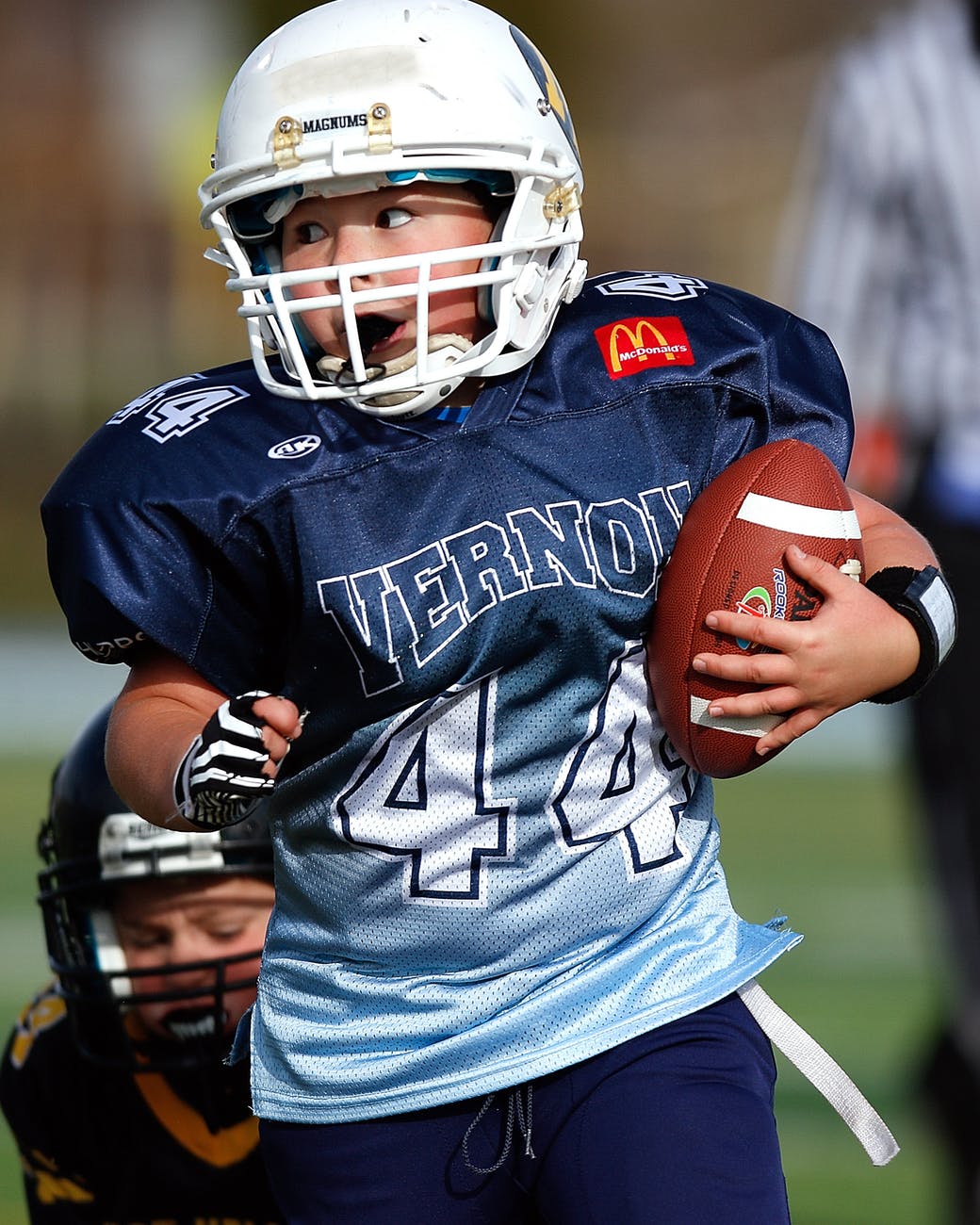 boy wearing football gear while holding football