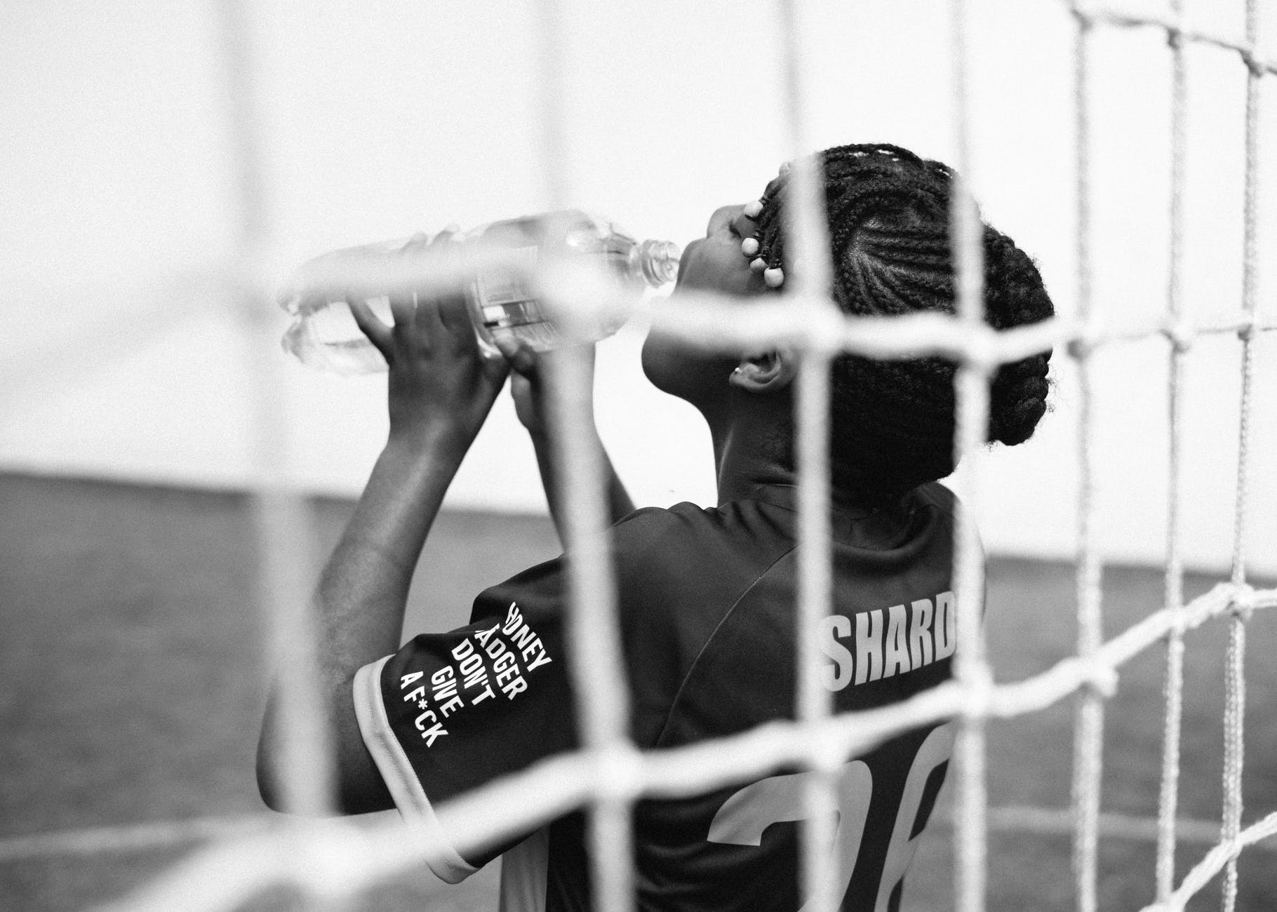 african american woman drinking while goalkeeping
